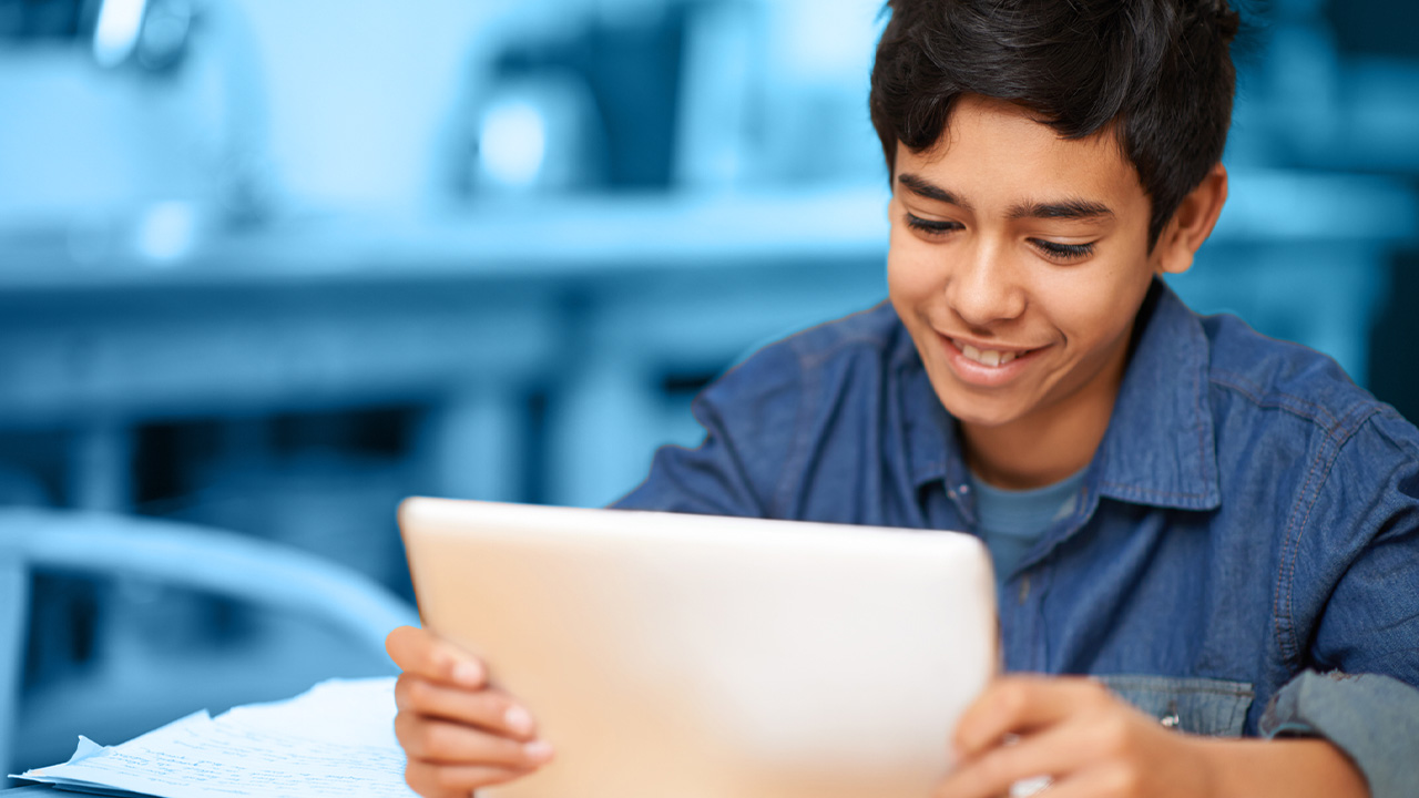 Student sitting at desk with tablet